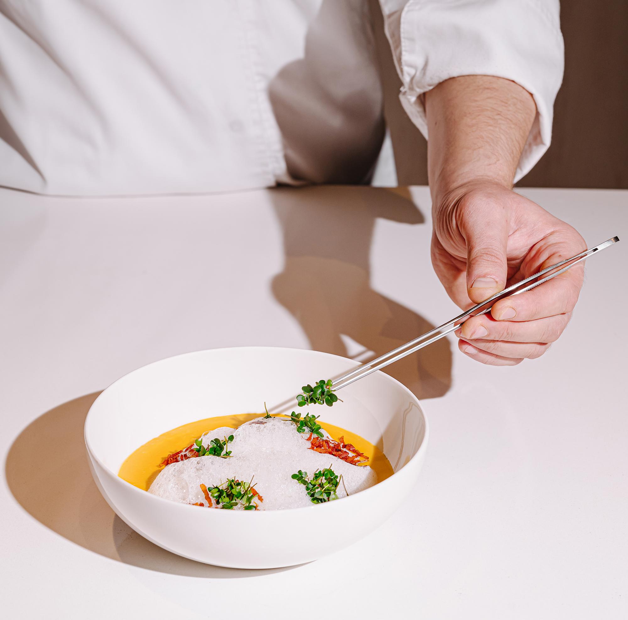 Chef arranging a plated dish in warm kitchen